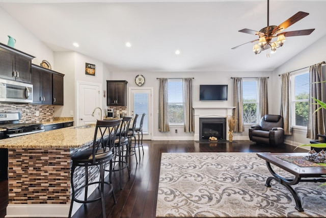 living room with vaulted ceiling, dark hardwood / wood-style floors, plenty of natural light, and sink