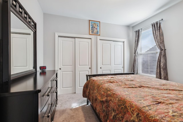 bedroom with light colored carpet and multiple closets