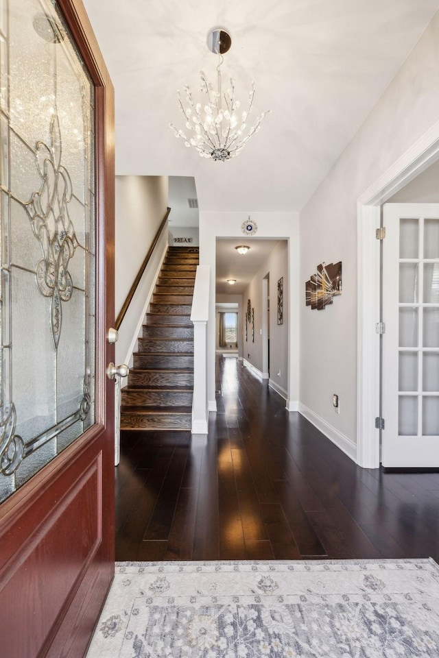 foyer featuring dark wood-type flooring and a chandelier