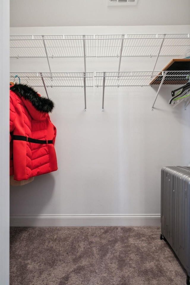 spacious closet with dark carpet and radiator