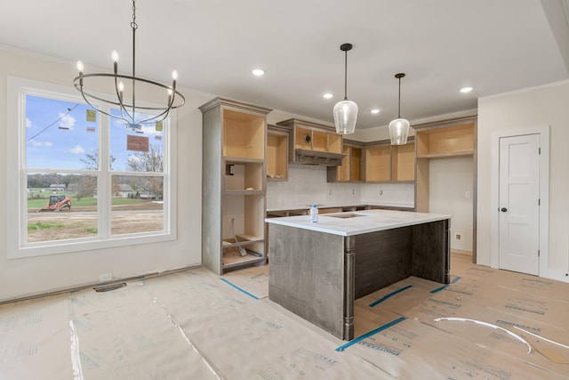 kitchen featuring backsplash, decorative light fixtures, crown molding, light stone counters, and a center island