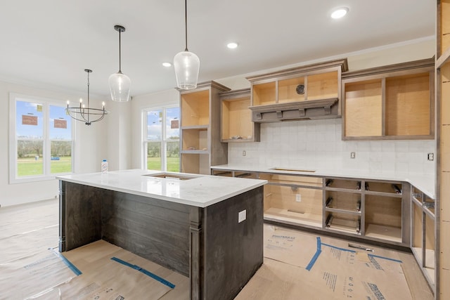 kitchen featuring light stone countertops, a center island, tasteful backsplash, hanging light fixtures, and ornamental molding