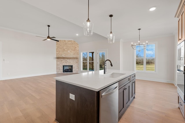 kitchen featuring a center island with sink, stainless steel appliances, light countertops, open floor plan, and a sink