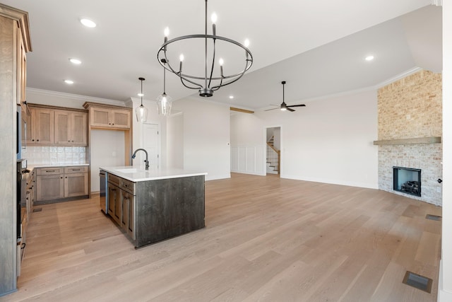 kitchen featuring stainless steel appliances, light countertops, open floor plan, a sink, and an island with sink