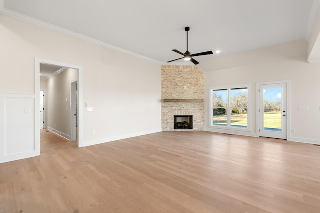 unfurnished living room with a large fireplace, light wood finished floors, a ceiling fan, and crown molding