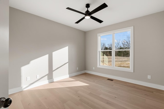 spare room featuring light wood-style floors, visible vents, ceiling fan, and baseboards