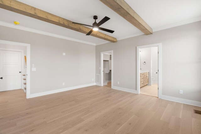 unfurnished bedroom with visible vents, baseboards, light wood-type flooring, beam ceiling, and a walk in closet