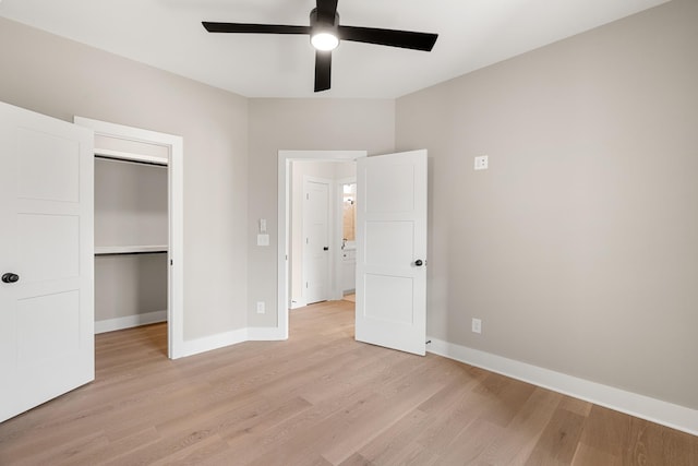 unfurnished bedroom with baseboards, a ceiling fan, a walk in closet, light wood-style floors, and a closet