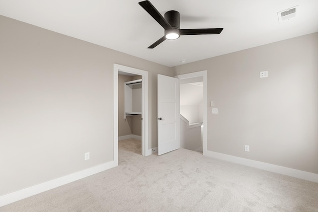 unfurnished bedroom with light carpet, baseboards, visible vents, ceiling fan, and a spacious closet