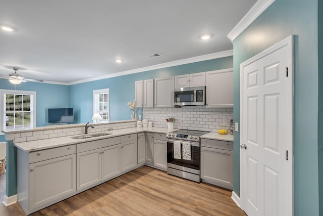 kitchen featuring decorative backsplash, sink, appliances with stainless steel finishes, and kitchen peninsula