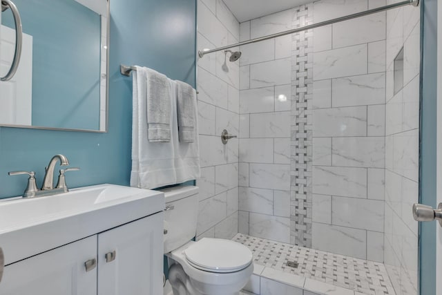 bathroom with toilet, tiled shower, and vanity