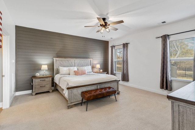 carpeted bedroom featuring wooden walls and ceiling fan