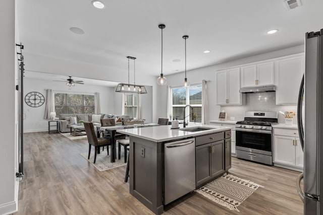 kitchen featuring pendant lighting, stainless steel appliances, sink, and white cabinets