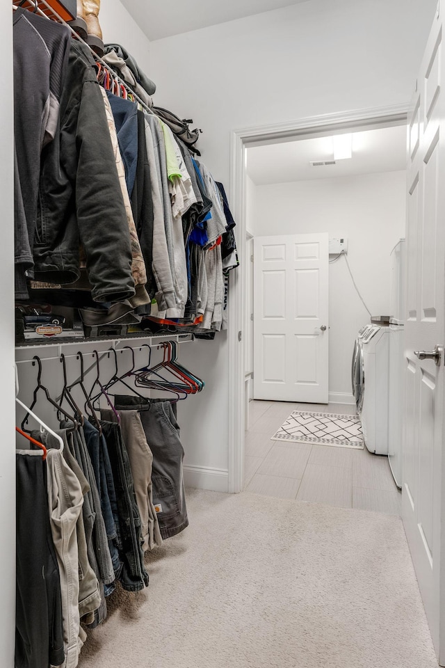 walk in closet with washer and dryer and light carpet