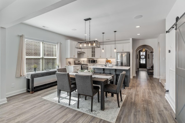 dining space featuring a barn door, sink, and light hardwood / wood-style flooring