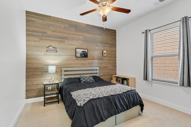 bedroom with ceiling fan, wooden walls, and light colored carpet