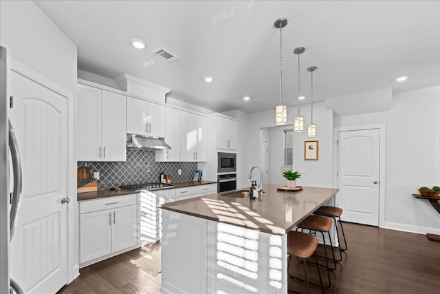 kitchen featuring pendant lighting, white cabinetry, stainless steel appliances, sink, and a center island with sink