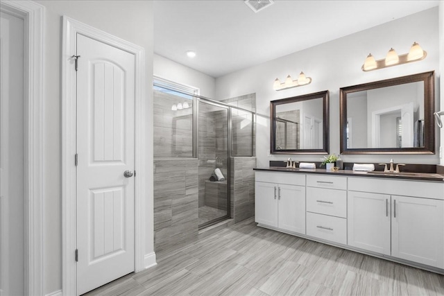 bathroom with a shower with shower door and vanity