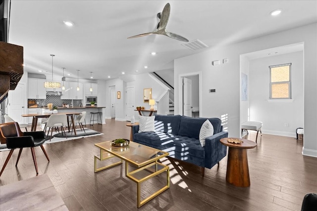 living room featuring ceiling fan and dark wood-type flooring