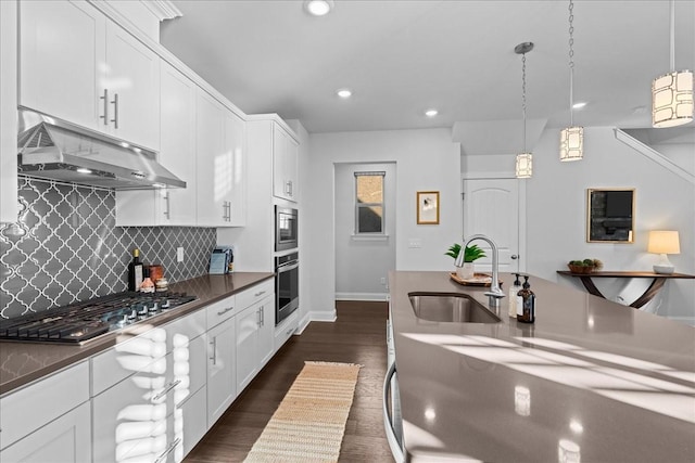 kitchen featuring white cabinets, stainless steel appliances, sink, backsplash, and hanging light fixtures