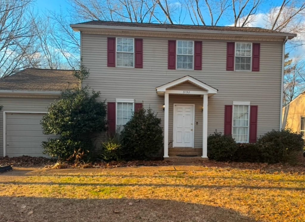 colonial-style house featuring a garage and a front yard