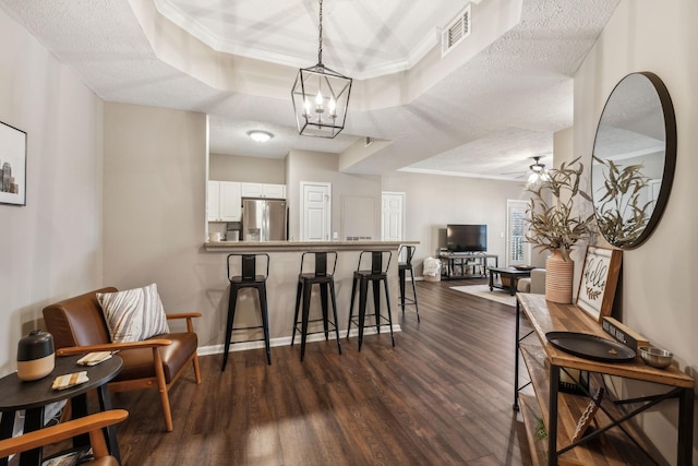 dining space featuring a textured ceiling, dark hardwood / wood-style floors, ceiling fan with notable chandelier, and a raised ceiling