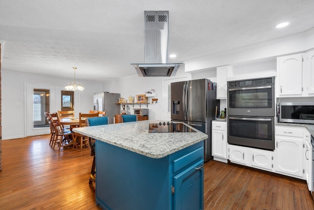 kitchen with white cabinetry, island range hood, appliances with stainless steel finishes, a kitchen island, and light stone counters