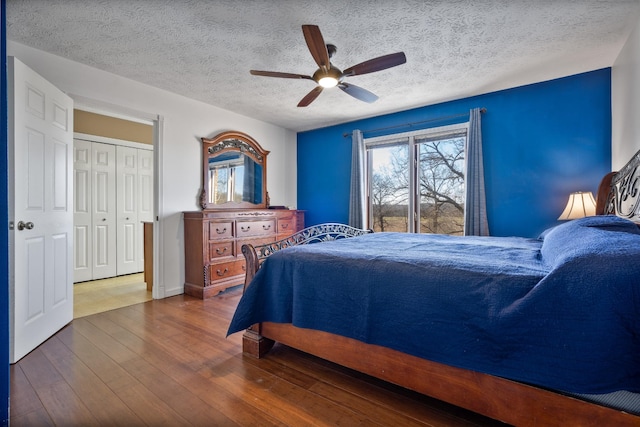 bedroom with a textured ceiling, ceiling fan, a closet, and hardwood / wood-style flooring