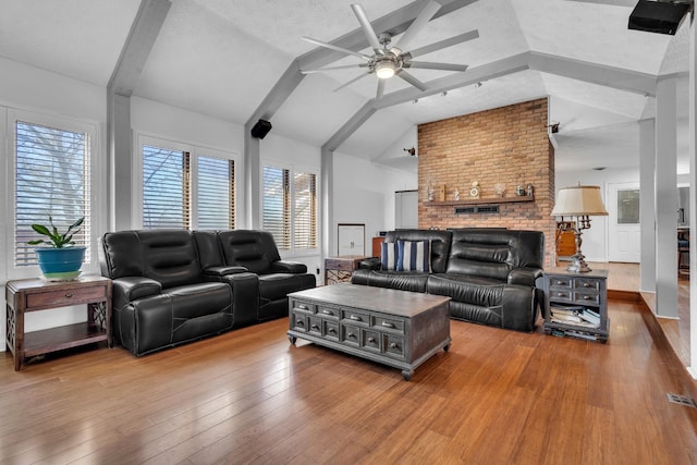 living room with a textured ceiling, lofted ceiling, a fireplace, ceiling fan, and hardwood / wood-style flooring