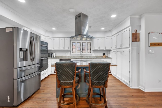 kitchen featuring island exhaust hood, stainless steel appliances, white cabinets, and a kitchen island