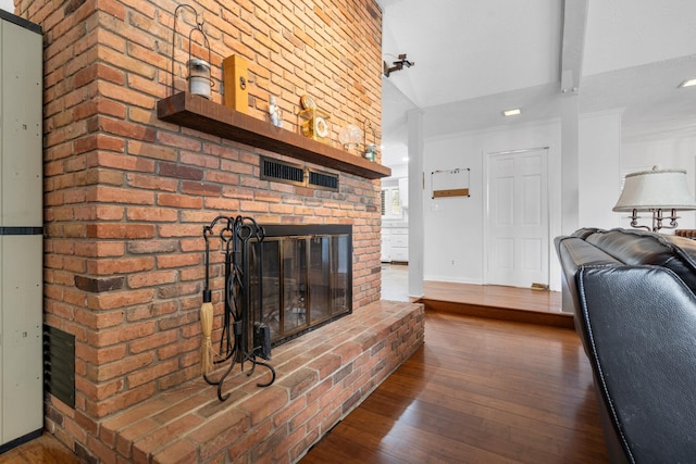 living room with wood-type flooring, a fireplace, and vaulted ceiling