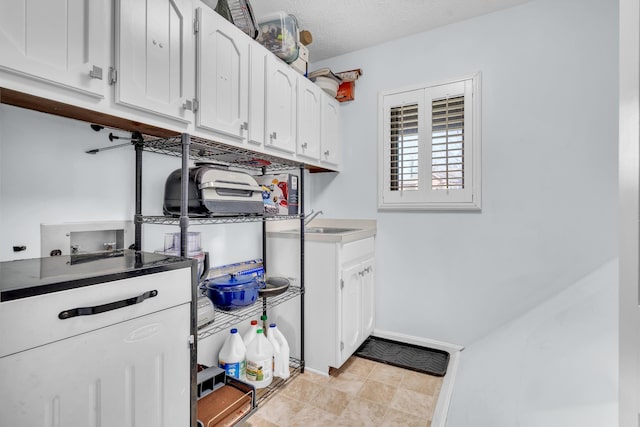 clothes washing area with a textured ceiling, cabinets, hookup for a washing machine, and sink