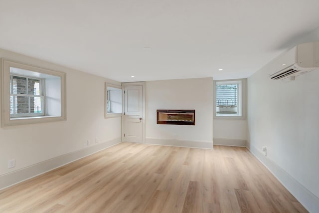 unfurnished living room featuring a fireplace, light hardwood / wood-style flooring, and a wall unit AC