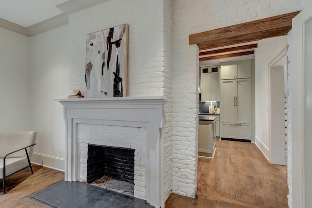 living room featuring beam ceiling, ornamental molding, a brick fireplace, and light hardwood / wood-style floors