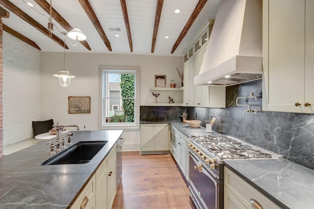 kitchen with sink, range with gas cooktop, custom exhaust hood, decorative light fixtures, and beam ceiling