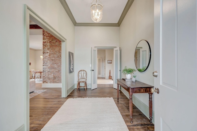 entrance foyer featuring an inviting chandelier, ornamental molding, and dark hardwood / wood-style floors