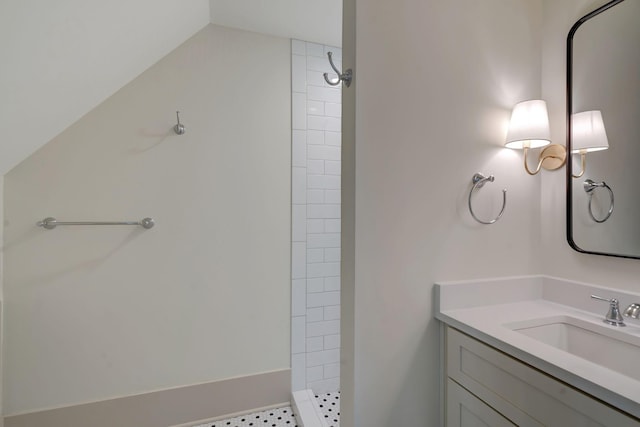 bathroom with vanity, lofted ceiling, and tiled shower