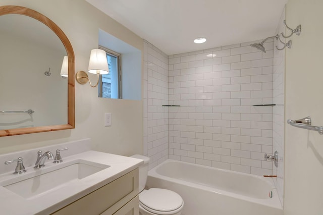 full bathroom featuring tiled shower / bath, vanity, and toilet