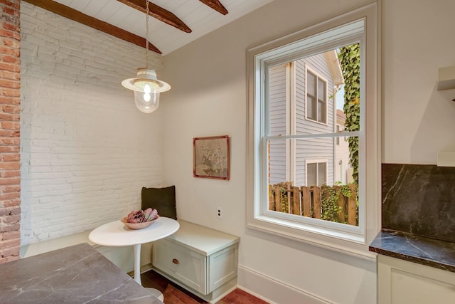 bathroom featuring lofted ceiling with beams and brick wall