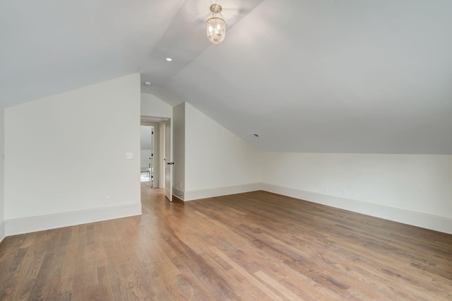 bonus room with wood-type flooring, a chandelier, and vaulted ceiling