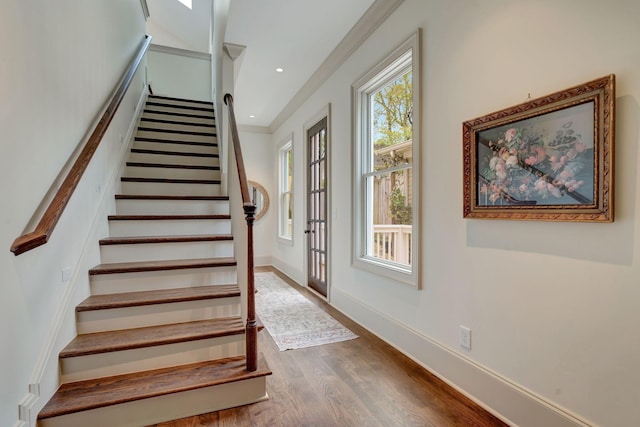 stairway with crown molding and hardwood / wood-style floors