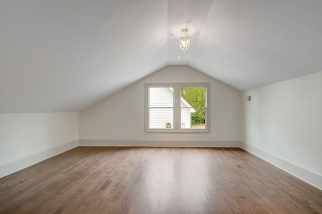 additional living space with hardwood / wood-style flooring and vaulted ceiling