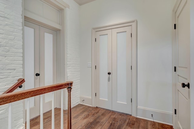 foyer entrance featuring brick wall and hardwood / wood-style floors