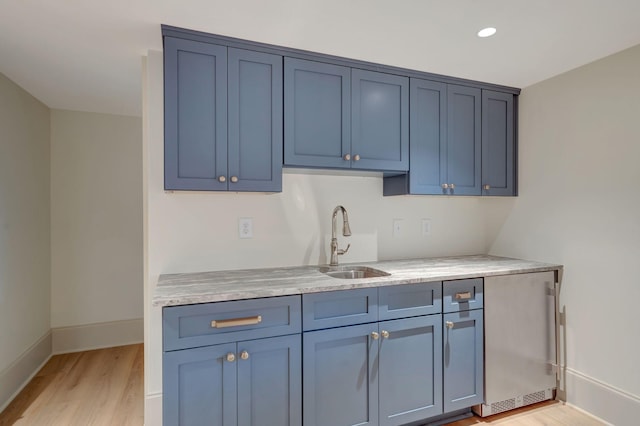 kitchen featuring sink, blue cabinetry, and light wood-type flooring