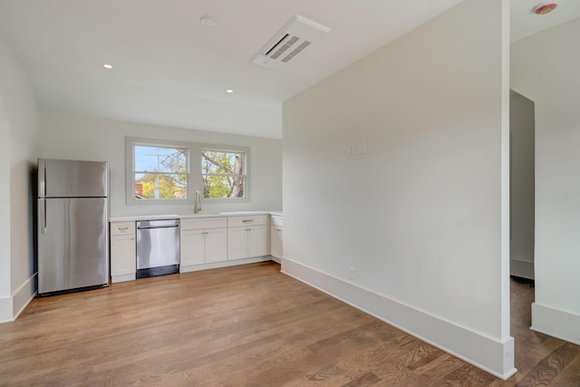 kitchen featuring stainless steel appliances, sink, white cabinets, and light wood-type flooring