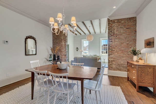 dining area with hardwood / wood-style flooring, brick wall, ornamental molding, and an inviting chandelier