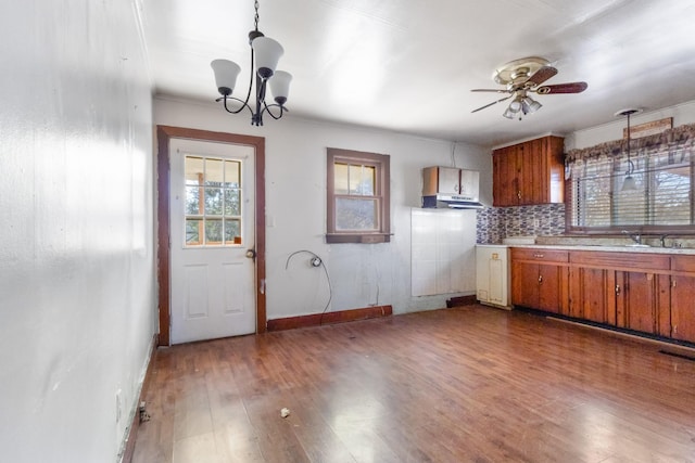 kitchen featuring pendant lighting, decorative backsplash, ceiling fan with notable chandelier, and dark hardwood / wood-style floors