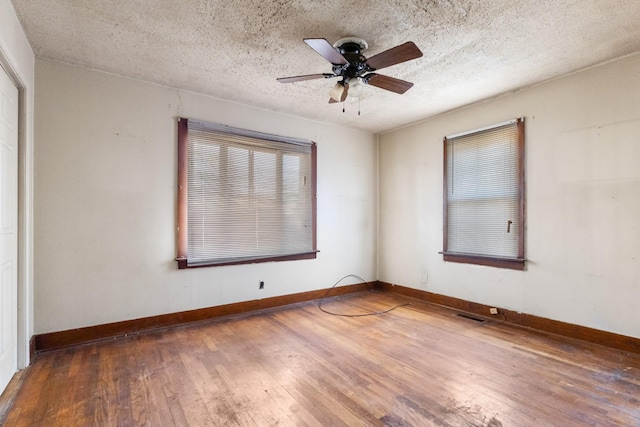 unfurnished room with ceiling fan, a textured ceiling, and dark hardwood / wood-style flooring