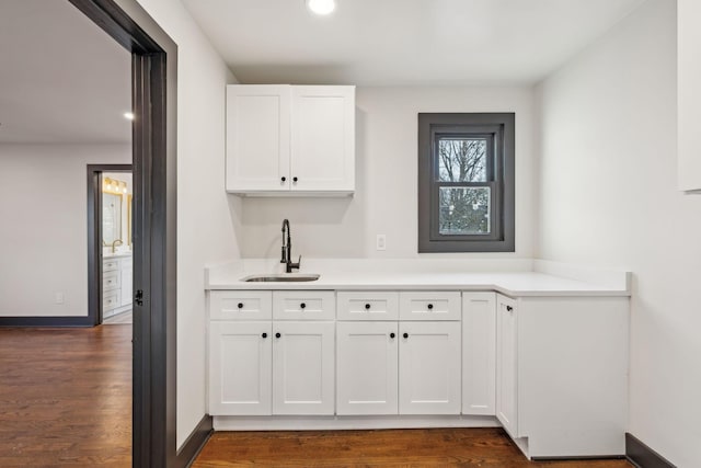 bar with sink, white cabinetry, and dark hardwood / wood-style flooring