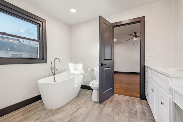 bathroom featuring a tub to relax in, vanity, and toilet